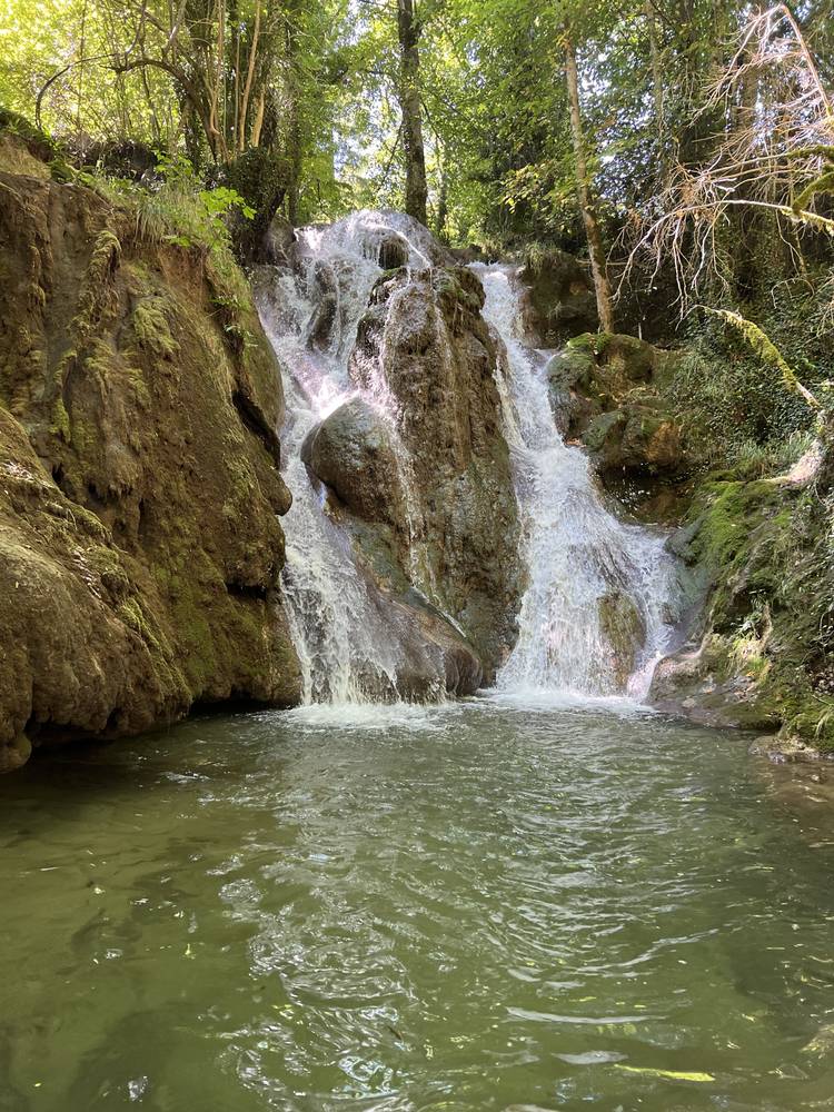 Cascade qui se jette dans un large bassin d'eau calme, la partie basse de l'image étant une zone lisse et vide