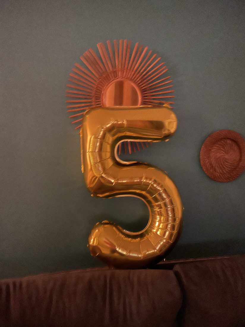 Un ballon gonflable doré en forme de chiffre posé sur un mur, photo du quotidien sans rapport avec la nature