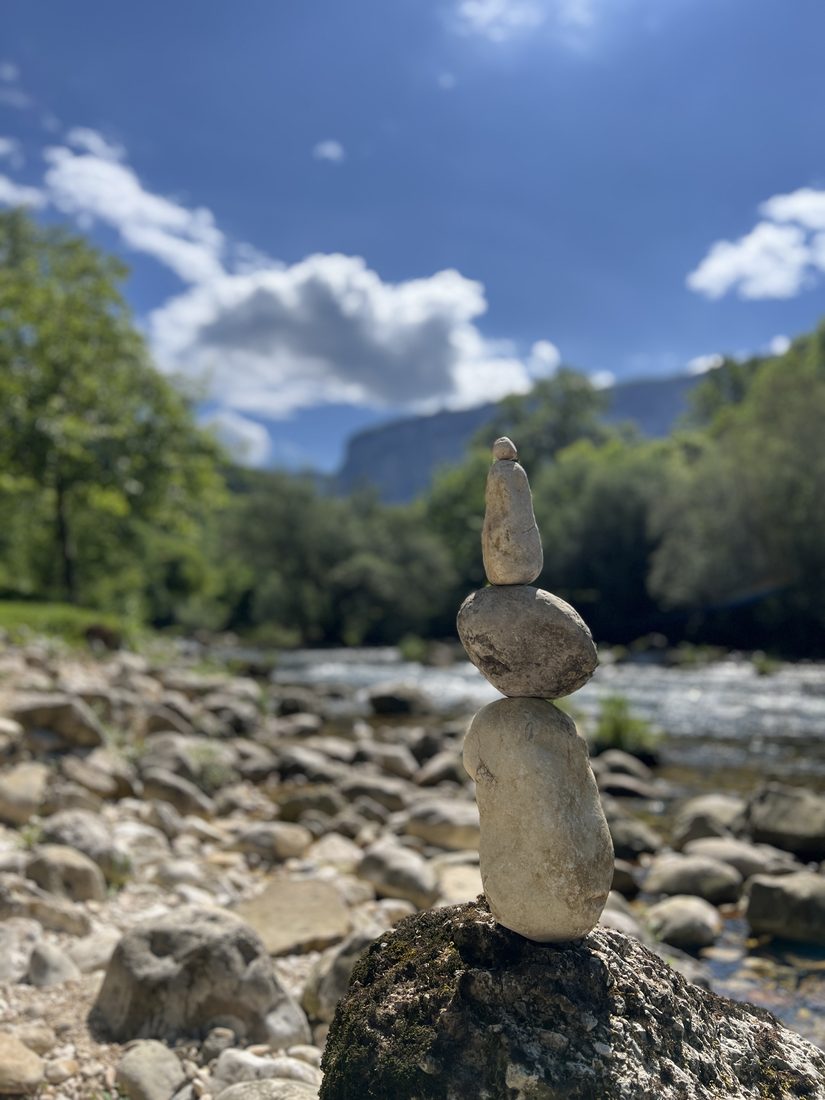 Un cairn de galets empilés en équilibre sur une pierre, au bord d'une rivière de montagne